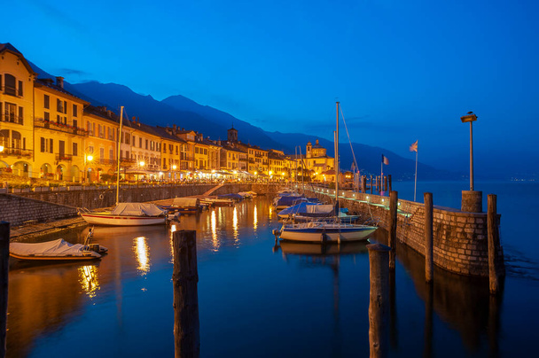 Haven in Cannobio met historische gevels langs de promenade van het Lago Maggiore. Op de achtergrond de bedevaartskerk Santuario della SS Pieta. Cannobio is een gemeente in de Italiaanse provincie Piëmont (regio Piëmont). - Foto, afbeelding
