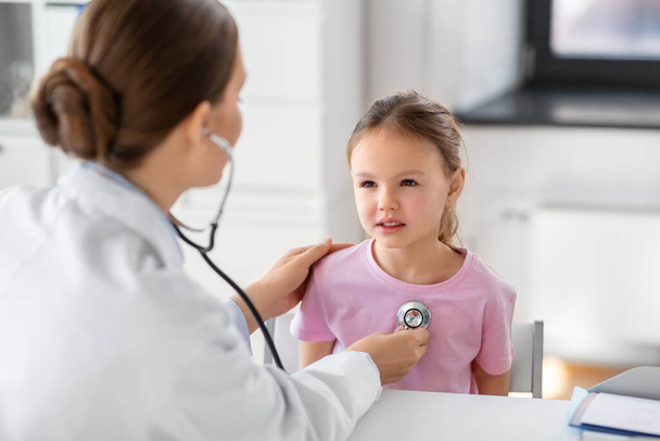 medicine, healthcare and pediatry concept - female doctor or pediatrician with stethoscope and little girl patient on medical exam at clinic - Foto, Imagem