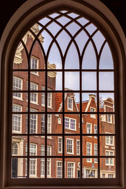 Προβολή μέσα από το παράθυρο μιας εκκλησίας στην εσωτερική αυλή του Begijnhof στο Άμστερνταμ, Ολλανδία - Φωτογραφία, εικόνα
