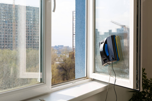 Robot nettoyeur de vitres travail sur vitre sale. Nettoyage de la maison avec des appareils intelligents. Robots aspirateurs automatiques pour nettoyer les fenêtres, un assistant pour la maison - Photo, image