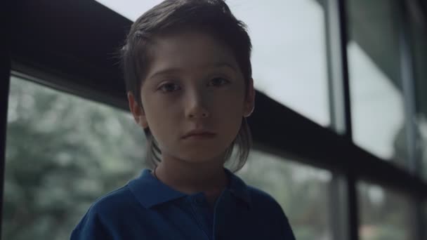 Portrait of upset teen boy looking camera standing near panorama window. Depressed little schoolboy posing alone feeling hopeless after conflict close up. Social rejection in school problem. - Footage, Video