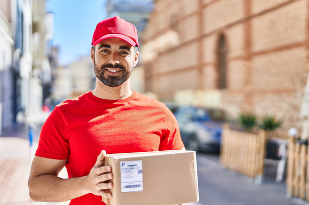 Jeune homme hispanique courrier tenant paquet à la rue - Photo, image