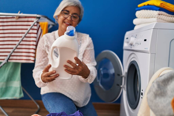 Жінка середнього віку миє одяг у пральні
 - Фото, зображення