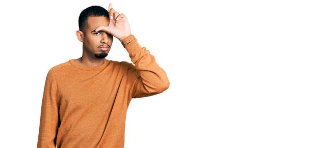 Jeune homme afro-américain portant des vêtements décontractés se moquant des gens avec les doigts sur le front faisant geste de perdant se moquant et insultant.  - Photo, image