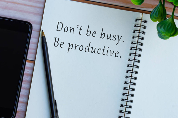 Motivatív és inspiráló idézet jegyzetfüzetben a fa íróasztalon - Ne légy elfoglalt, légy produktív. - Fotó, kép