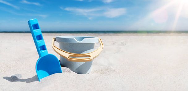 海と青空を背景に砂のビーチでおもちゃのバケツとスペードのクローズアップビュー - 写真・画像
