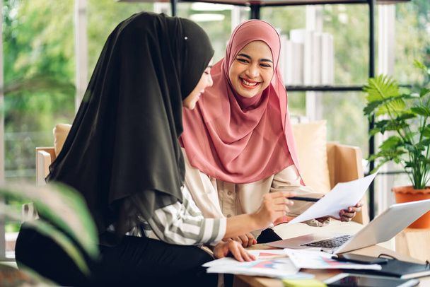 Jovens dois sorrindo feliz bela mulher muçulmana asiática relaxante usando computador portátil trabalhando e reunião analisando discutir estratégia com plano de projeto de inicialização e brainstorm em casa - Foto, Imagem