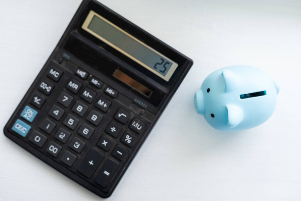 Piiggy bank avec calculatrice close-up sur fond bleu pastel. Calcul du budget familial, épargne. Minimalisme - Photo, image