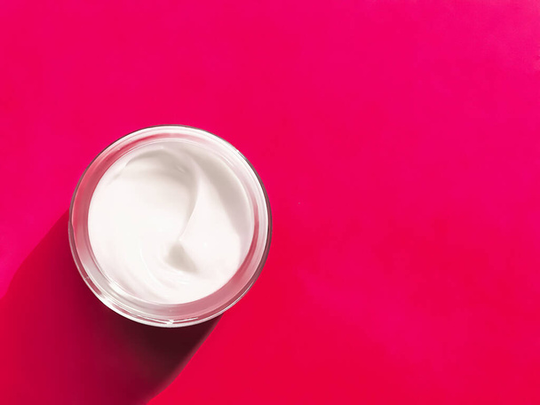 Crema facial hidratante tarro sobre vidrio y fondo rosa, producto de belleza y cuidado de la piel, concepto de ciencia cosmética - Foto, imagen