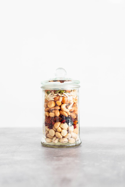 glass jar of mixed nuts including almonds cashews and pistachios, concept of natural healthy pantry ingredients - Foto, afbeelding
