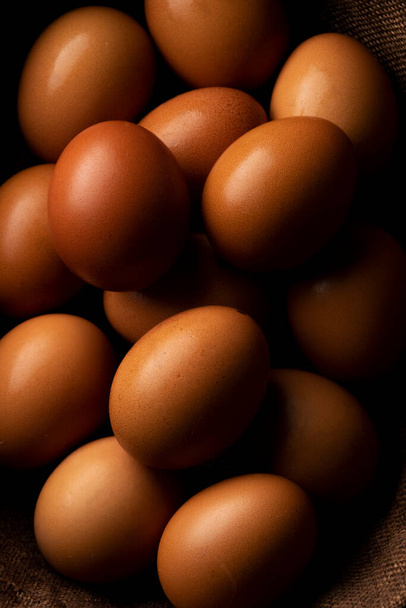 Czerwone jaja kurze na ciemnym rustykalnym stole, organiczne składniki żywności - Zdjęcie, obraz