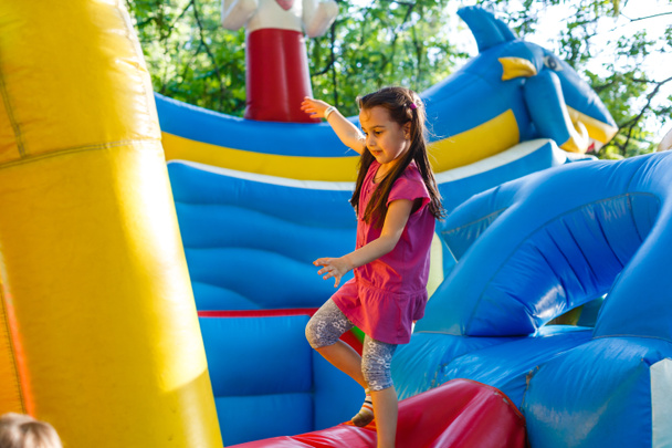 Un niño alegre juega en un castillo inflable. - Foto, imagen