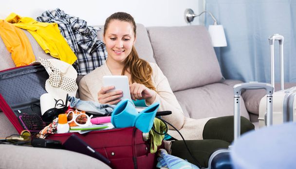 Young glad woman packing luggage for holidays indoors - Foto, afbeelding