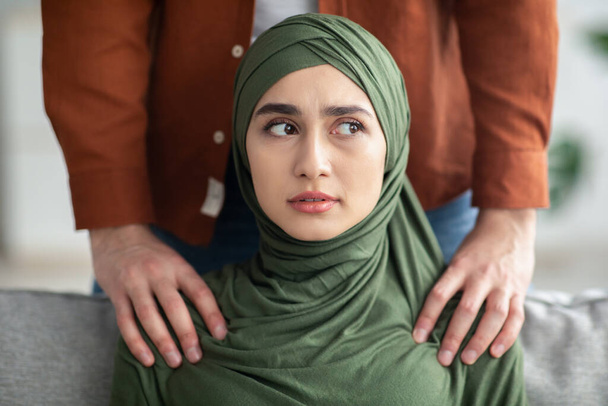 Unrecognizable Middle Eastern Man Touching Scared Womans Shoulders Threatening Her Standing Indoors. Workplace Harassment Problem And Domestic Abuse Concept. Cropped - Photo, Image