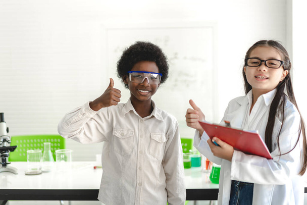 Grupa nastolatek uroczy mały uczeń dziecko uczyć się nauki badania naukowe i nauka robi chemicznego eksperyment robi analizować i mieszać ciecz w probówce na zajęciach w szkołach.Edukacja - Zdjęcie, obraz
