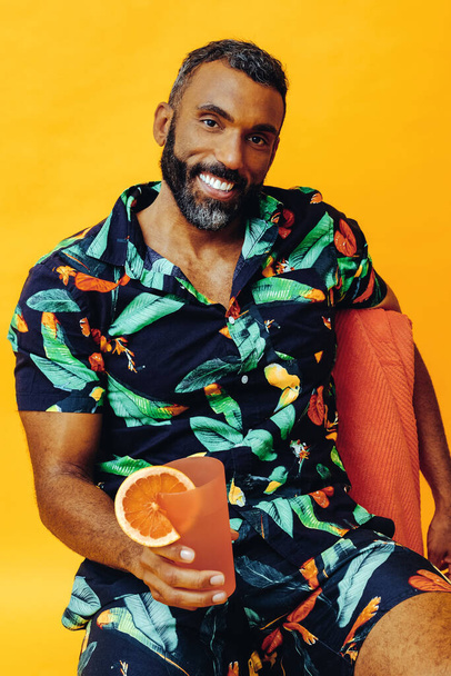 portré fiatal afro-amerikai férfi kezében koktél friss ital sárga háttér - Fotó, kép
