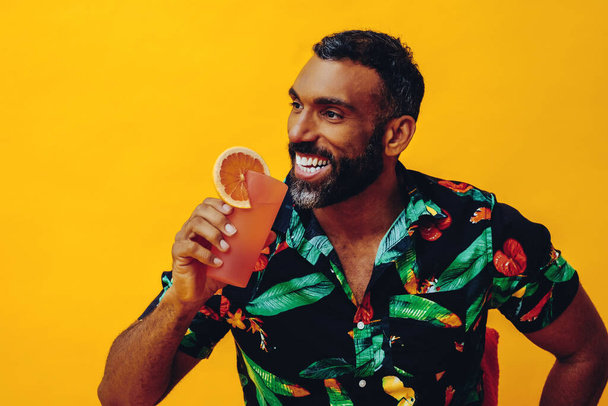 ritratto di giovane uomo afroamericano che tiene cocktail con bevanda fresca sullo sfondo giallo - Foto, immagini