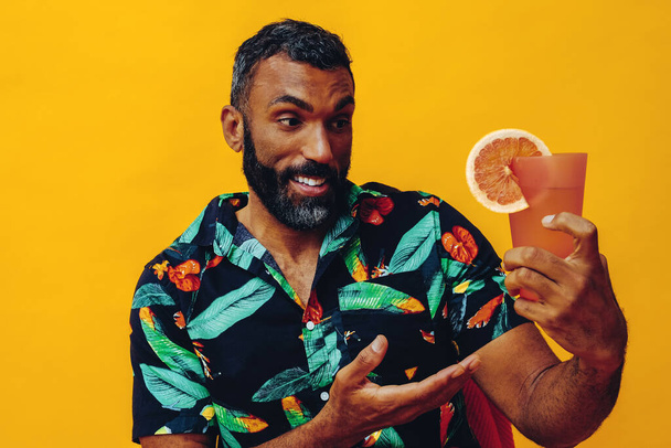 retrato de un joven afroamericano sosteniendo cóctel con bebida fresca sobre fondo amarillo - Foto, imagen