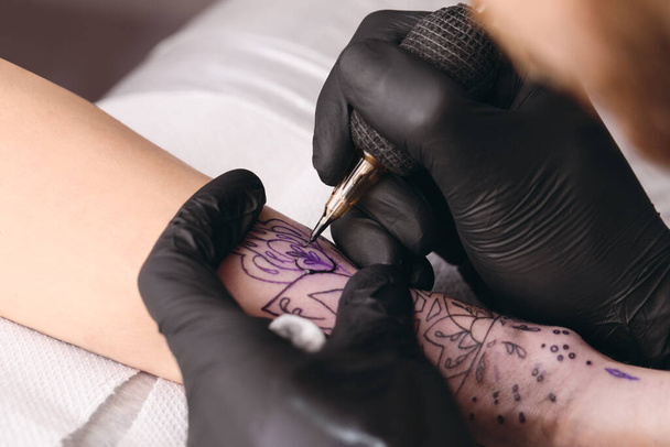 Professional artist making tattoo on hand at table, closeup - Foto, Imagen