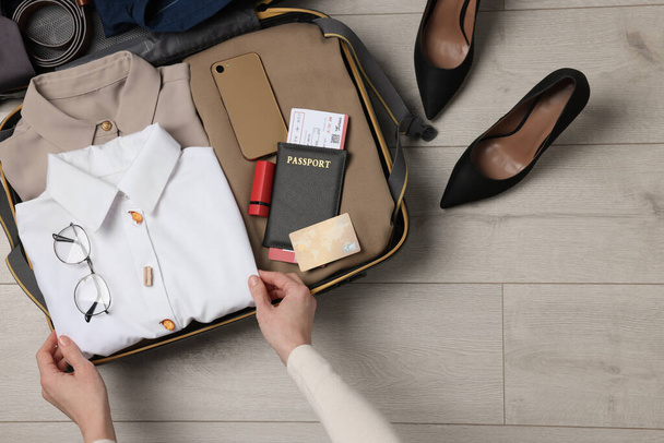 Woman packing suitcase on wooden floor, top view with space for text. Business trip planning - Foto, imagen