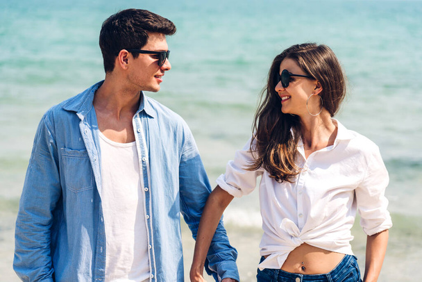 Vacaciones amor romántico joven sonrisa feliz pareja en viaje de luna de miel viaje de vacaciones de pie en la arena en el cielo azul mar playa divertirse y relajarse juntos en la playa tropical. - Foto, imagen