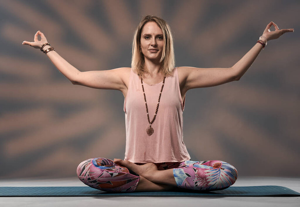 Young woman yoga trainer in asana posture, studio shot - Foto, Imagem
