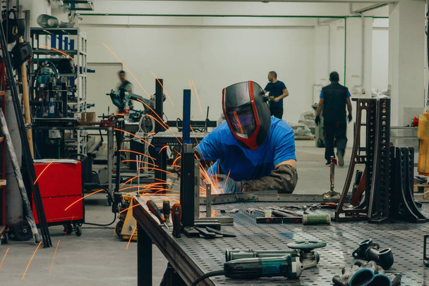 Professional Heavy Industry Welder Working Inside the factory, Wears Helmet and Starts Welding. Selective Focus. High-quality photo - Foto, Imagen