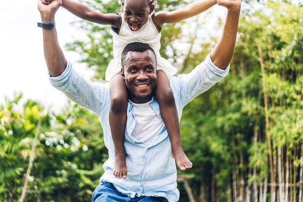 Retrato de desfrutar de amor feliz família negra afro-americano pai carregando filha pequena menina africana criança sorrindo e se divertindo momentos bons no parque de verão em casa - Foto, Imagem