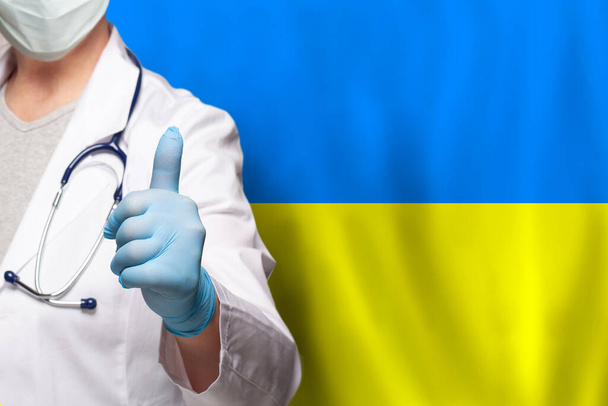Doctor's hand showing thumb up positive gesture on flag of Ukraine background - Fotó, kép
