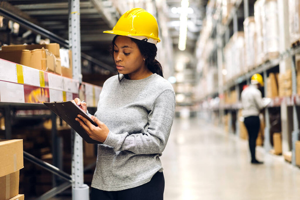 Portrait african american engineer woman shipping order detail on tablet check goods and supplies on shelves with goods inventory in factory warehouse.logistic industry and business export - Photo, Image