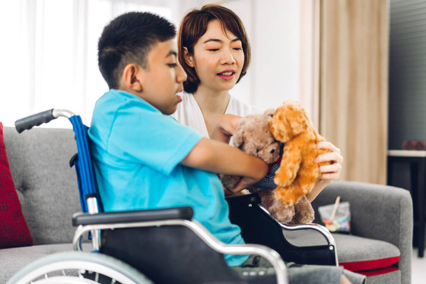 Portrait of enjoy happy love family asian mother playing and carer helping look at disabled son child sitting in wheelchair moments good time at home.disability care concept - Photo, Image