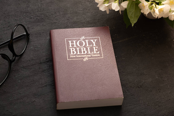A Szent Biblia legfelső nézete az asztalon szemüveggel. A bibliaismeret fogalma. - Fotó, kép