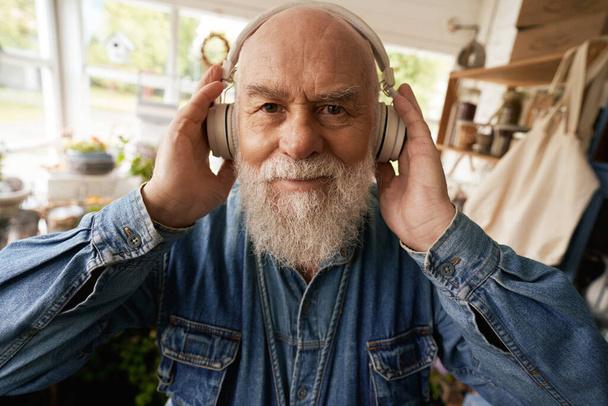 Portret starszego brodatego mężczyzny bawiącego się dobrze słuchając muzyki podczas dnia pracy jako kwiaciarnia - Zdjęcie, obraz