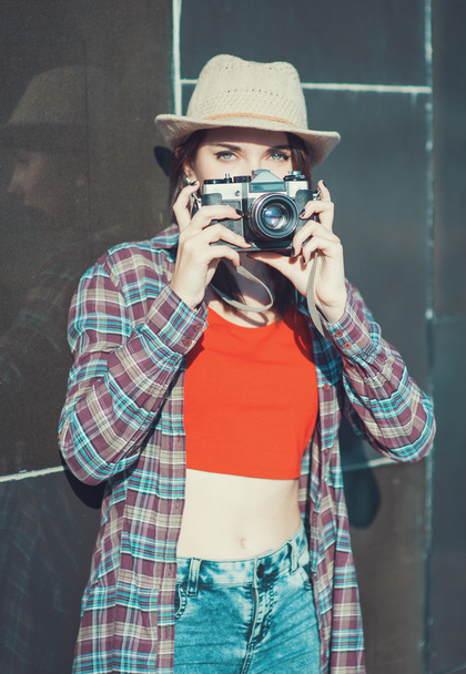 Hipster girl making picture with retro camera, focus on camera - Photo, Image