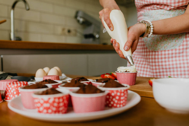 Woman preparing tasty Easter cupcake in kitchen - Foto, Bild