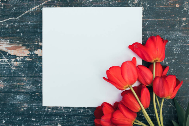 Fresh tulips bouquet and blank card for copy space over wooden table background - Foto, Imagem