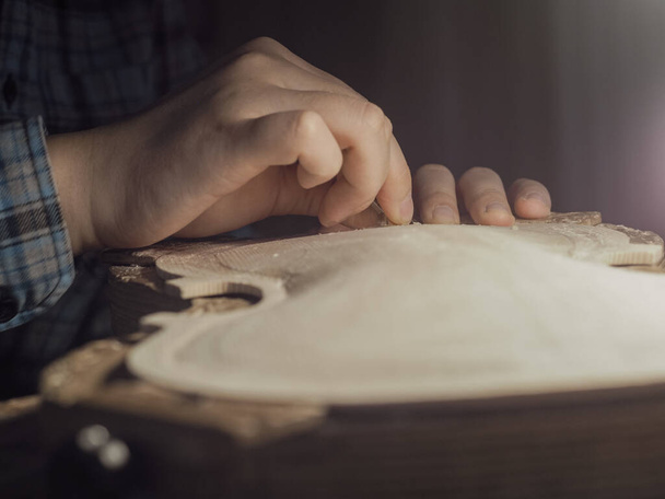 artesano trabajando sobre placa de violín de madera en bruto con el dedo plano en el banco - Foto, imagen