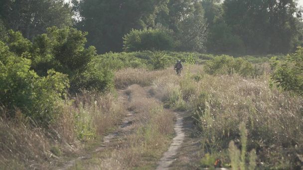 Man exploring single track trail on mountain bike. Male athlete mountainbiker rides bicycle along country road in summer. Sport and healthy life. Cyclist on country road. Biking on cross country road. - Photo, Image