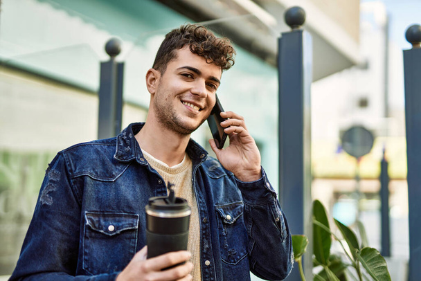 Joven hispano hablando en el smartphone tomando café en la ciudad - Foto, imagen