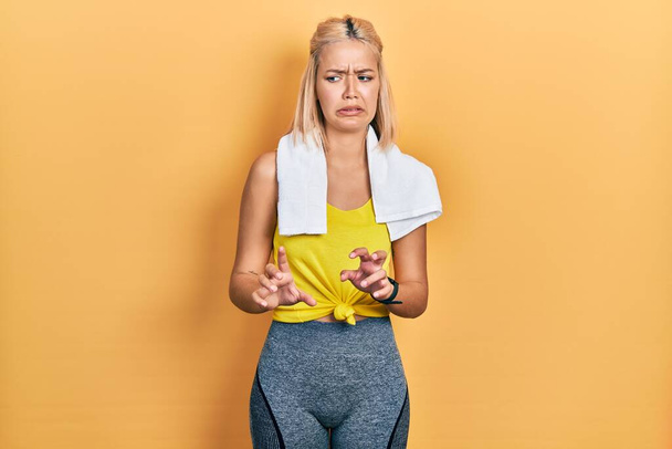 Beautiful blonde sports woman wearing workout outfit disgusted expression, displeased and fearful doing disgust face because aversion reaction.  - Foto, imagen