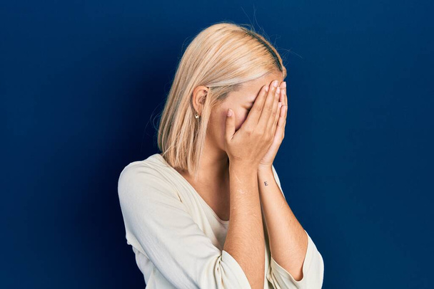 Krásná blondýnka na sobě ležérní svetr se smutným výrazem zakrývající tvář s rukama při pláči. deprese koncept.  - Fotografie, Obrázek