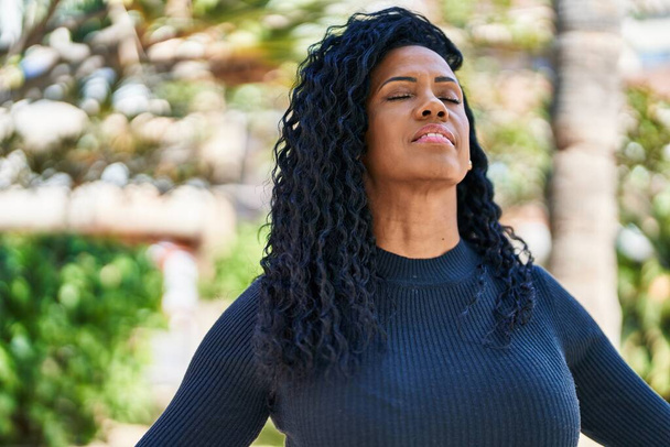 afroamericano donna sorridente fiducioso respirazione a parco - Foto, immagini