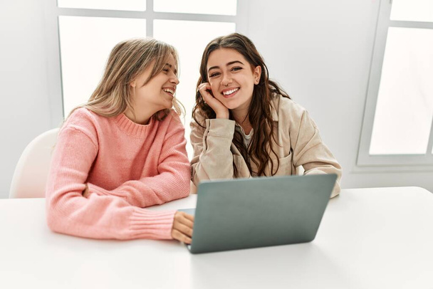 Молодая пара улыбается счастливая работа с ноутбуком дома. - Фото, изображение
