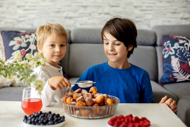 Cute child, boy with pet dog, eating fried doughnuts at home with his siblings, sweet breakfast - Fotoğraf, Görsel