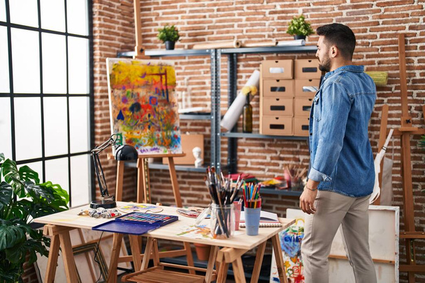 Jeune homme hispanique regardant le dessin debout au studio d'art - Photo, image