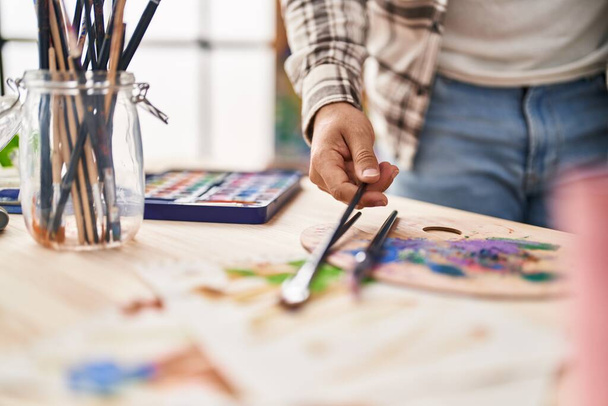 Joven hispano sosteniendo pincel en el estudio de arte - Foto, Imagen