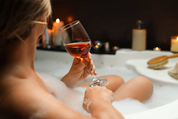 Woman drinking wine while taking bubble bath, closeup. Romantic atmosphere - Photo, image