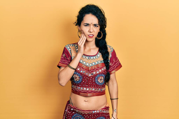 Young woman wearing bindi and bollywood clothing touching mouth with hand with painful expression because of toothache or dental illness on teeth. dentist  - 写真・画像