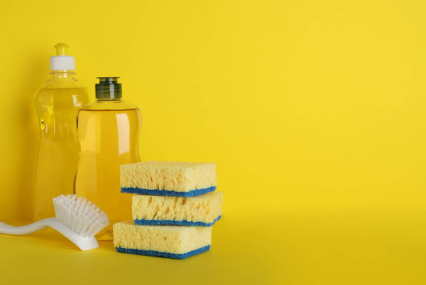 Spugne e altri prodotti per la pulizia su fondo giallo. Spazio per testo - Foto, immagini