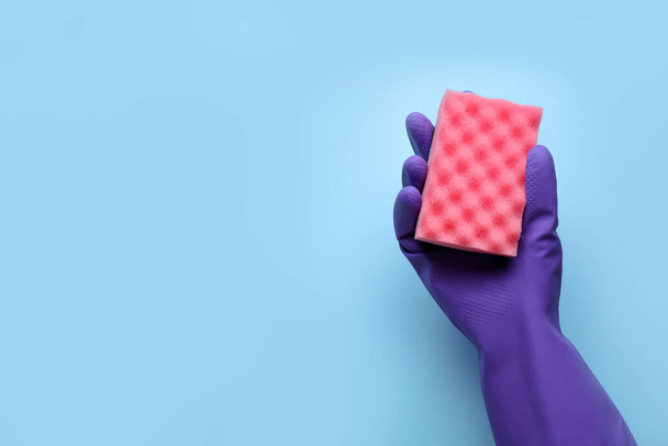 Woman in rubber glove holding sponge on light blue background, top view. Space for text - Fotó, kép